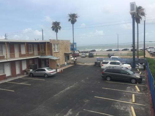 un estacionamiento con autos estacionados frente a un edificio en Beachtree Motel en Galveston