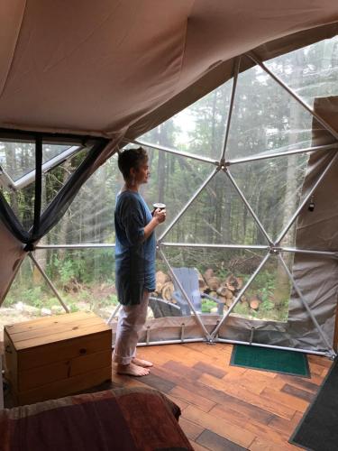 a woman standing in a tent looking out the window at Centre de l'Hêtre in Lac-Beauport