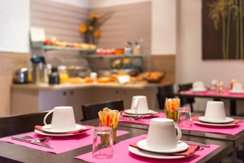 a table with pink napkins and hats on top at Hotel Le 21 in Saint-Raphaël