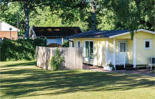 a small yellow house with a fence in a yard at Lovely Home In Färjestaden in Färjestaden