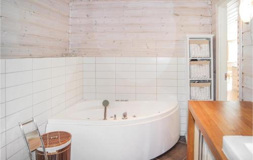 a white tub in a white tiled bathroom at Amazing Home In Hol With Sauna in Seim