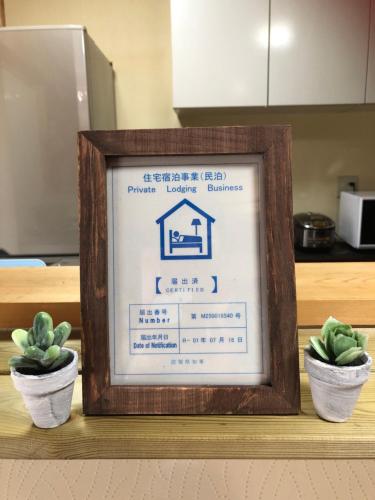 a framed sign on a shelf with two potted plants at familie in Otsu