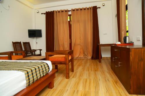a bedroom with a bed and a desk and a television at Heaven in Satinwoods in Tangalle