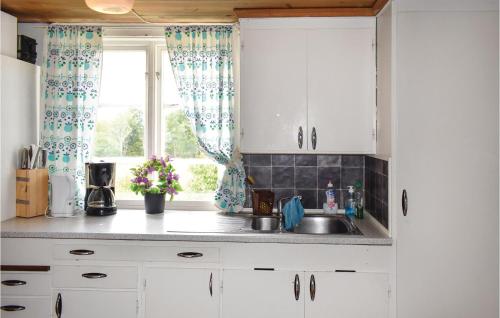 a kitchen with white cabinets and a sink and a window at Holiday Home Rökulla Mariannelund in Mariannelund