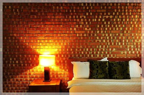 a bedroom with a brick wall with a bed and a lamp at Chang House in Zhuangwei