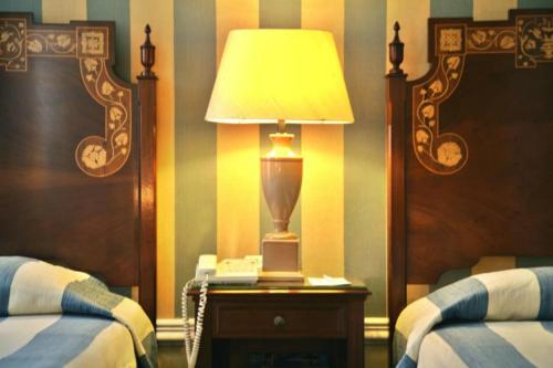 a bedroom with two beds and a lamp on a table at Hotel Avenida Palace in Lisbon