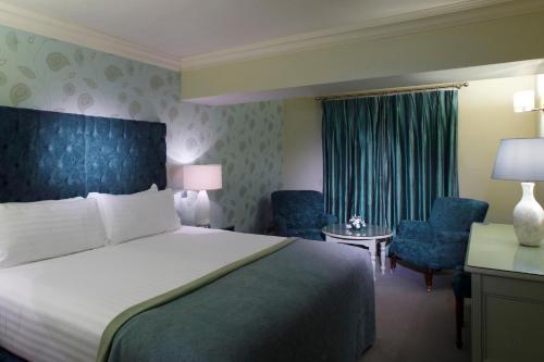 a hotel room with a bed and two chairs at Old Ground Hotel in Ennis