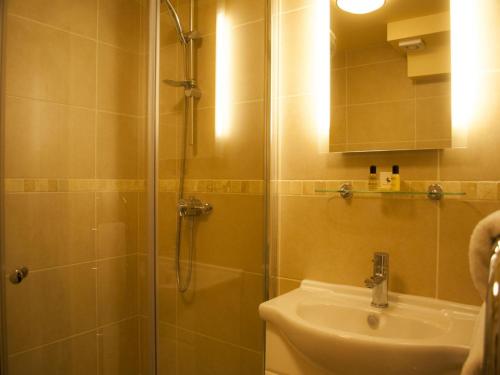 a bathroom with a shower, sink, and mirror at The North Hill Hotel in Colchester