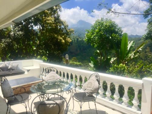 a balcony with chairs and a table and a large window at Pondok Plantation Luxury Mountain Escape Bedugul in Bedugul