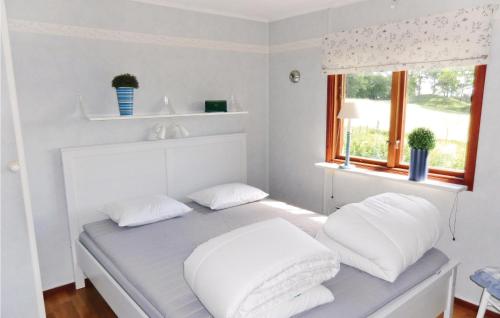 a bed with white pillows in a room with a window at Stunning Home In Landsbro With Kitchen in Landsbro