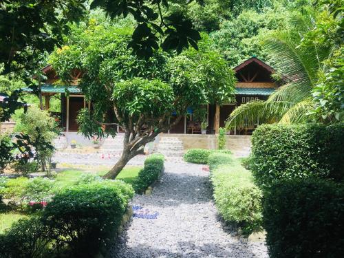 a garden with a tree and bushes and a building at Sahnan Guest House in Bukit Lawang