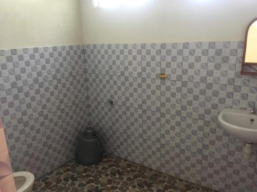 a tiled bathroom with a sink and a toilet at Sahnan Guest House in Bukit Lawang