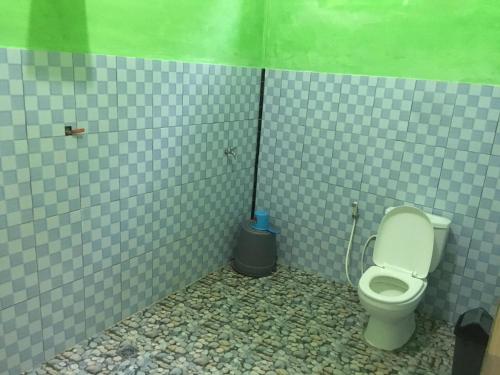 a bathroom with a toilet in a tiled stall at Sahnan Guest House in Bukit Lawang