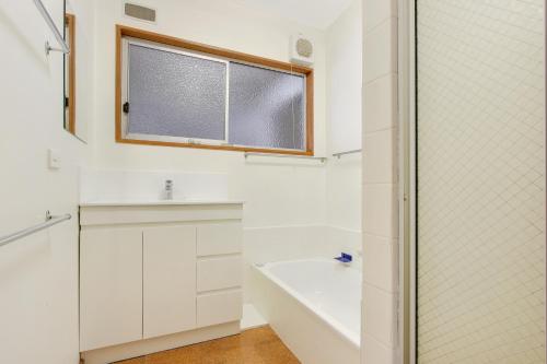 a bathroom with a tub and a sink and a window at Herons Rise in Metung