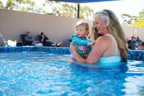 a woman holding a baby in a swimming pool at BIG4 Swan Hill in Swan Hill