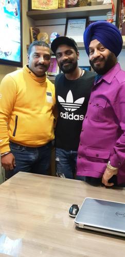 three men standing next to a table with a laptop at Hotel Makhan Residency in Amritsar