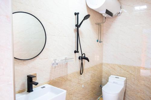 a bathroom with a shower and a toilet and a mirror at New Dap Hostel (in Grape Town) in Turfan