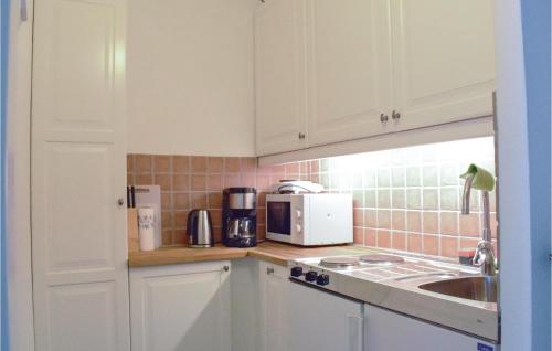a kitchen with white cabinets and a sink and a microwave at Amazing Apartment In Ystad With Kitchen in Ystad