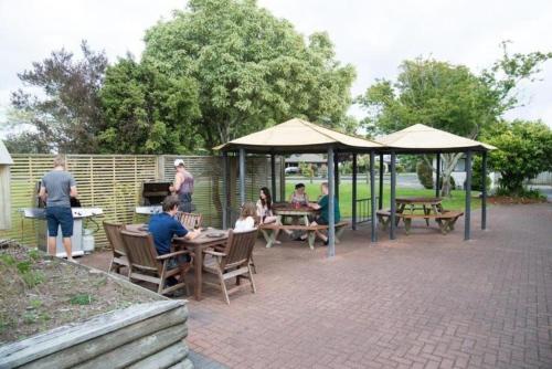 a group of people sitting at tables under a gazebo at Holdens Bay Holiday Park in Rotorua