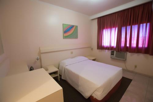 a hotel room with two beds and a window at Prince Hotel in Ribeirão Preto