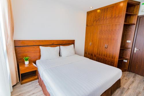 a bedroom with a white bed and a wooden cabinet at Hana Stay Trần Quốc Hoàn in Hanoi