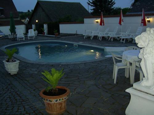a swimming pool with chairs and a table and a statue at Pension Šejko in Horní Planá