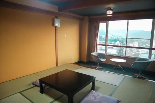 a living room with a table and chairs and a window at Hotel&Resort Yamanouchi Hills in Yamanouchi