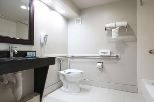 a white bathroom with a toilet and a sink at Best Western Lanai Garden Inn & Suites in San Jose