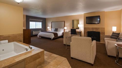 a large hotel room with a bed and a bath tub at Best Western PLUS Cotton Tree Inn in North Salt Lake