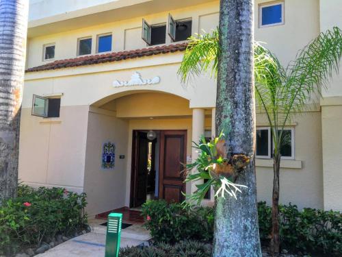 una casa con una palmera delante de ella en Villa Iris 2 story ocean view villa w/ pool access en Vega Alta