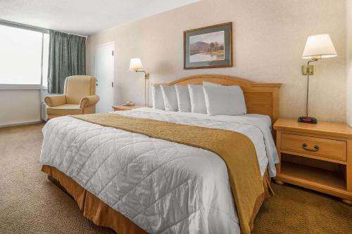 a hotel room with a large bed and a chair at Econo Lodge Rawlins in Rawlins