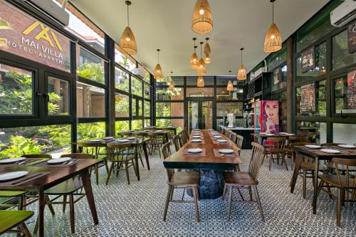 a restaurant with wooden tables and chairs and windows at MAI Villa Da Nang in Da Nang