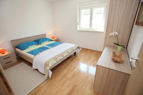 a bedroom with a bed with blue pillows and a window at Villa Iris Apartments in Seget Vranjica