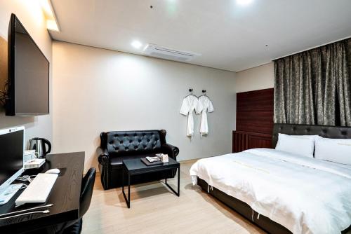 a bedroom with a bed and a chair and a desk at Siheung Seoul Tourist Hotel in Siheung