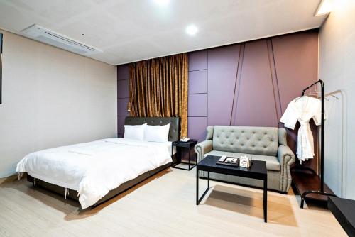 a bedroom with a bed and a couch and a table at Siheung Seoul Tourist Hotel in Siheung