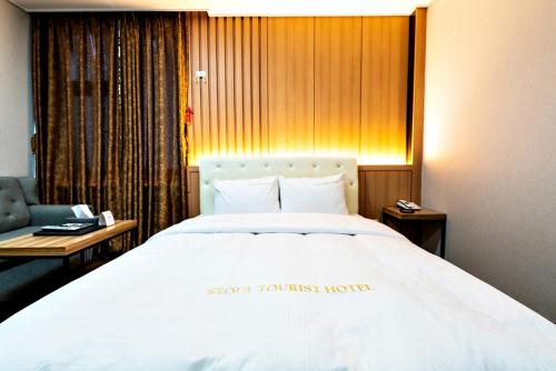 a bedroom with a large white bed and a chair at Siheung Seoul Tourist Hotel in Siheung