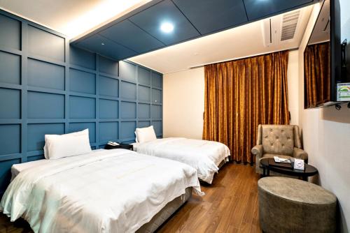 a hotel room with two beds and a chair at Siheung Seoul Tourist Hotel in Siheung