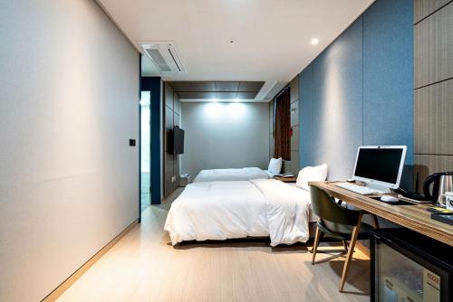 a bedroom with a bed and a desk with a computer at Siheung Seoul Tourist Hotel in Siheung
