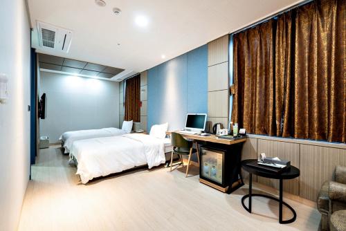 Siheung Seoul Tourist Hotel في Siheung: غرفة في الفندق بها سرير ومكتب وبه جهاز كمبيوتر