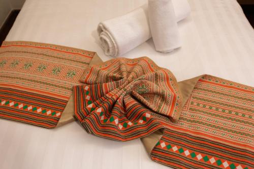 two ties on a bed with a roll of toilet paper at Lima Lanna Hotel in Chiang Mai