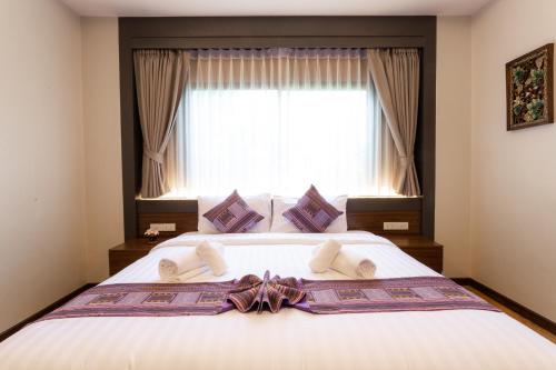 a bedroom with a large bed with a window at Lima Lanna Hotel in Chiang Mai