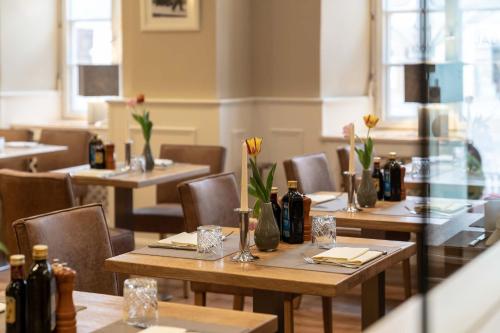 a restaurant with tables and chairs with bottles on them at Hotel Vollmann in Weilheim in Oberbayern