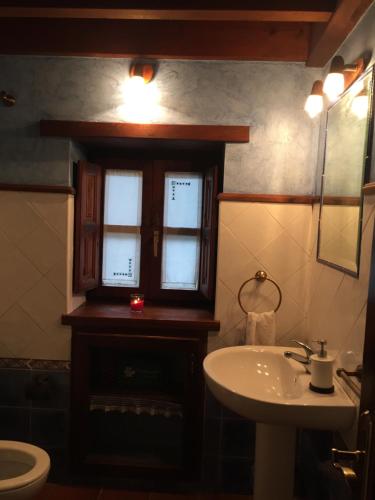 baño con lavabo y aseo y ventana en Casa rural Espinareu en Espinaredo