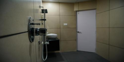 a bathroom with a shower with a white door at Nextel Inn, Calicut in Kozhikode