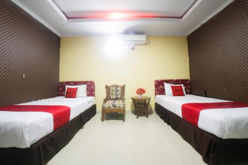 um quarto com duas camas e uma cadeira em RedDoorz Syariah near RSUD Ainun Habibie Gorontalo em Limboto