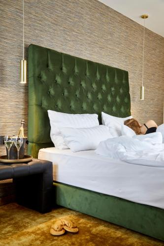 a bedroom with a large bed with a green headboard at Das Carls Hotel in Düsseldorf