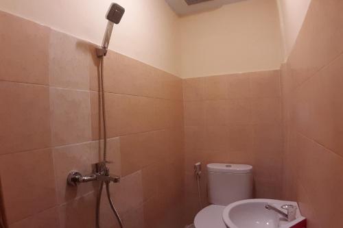 een badkamer met een douche, een toilet en een wastafel bij OYO 1053 Angelyn Home Stay in Medan