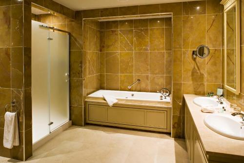 een badkamer met een bad, 2 wastafels en een douche bij Knockranny House Hotel & Spa in Westport