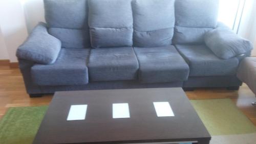 Sofá azul en la sala de estar con mesa de centro en Precioso apartamento en Lugo