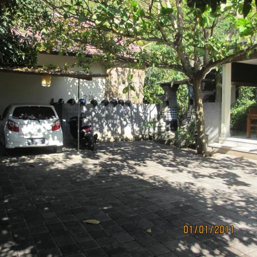 a car parked under a tree in a driveway at Pondok Aldi Hostel in Amed